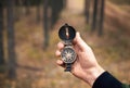 Compass in manÃ¢â¬â¢s hand in forest for searching for right direction